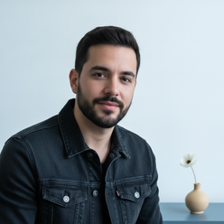 Portrait of male influencer Marcello Silva, @silva_creatives, smiling confidently, wearing a dark wash denim jacket against a